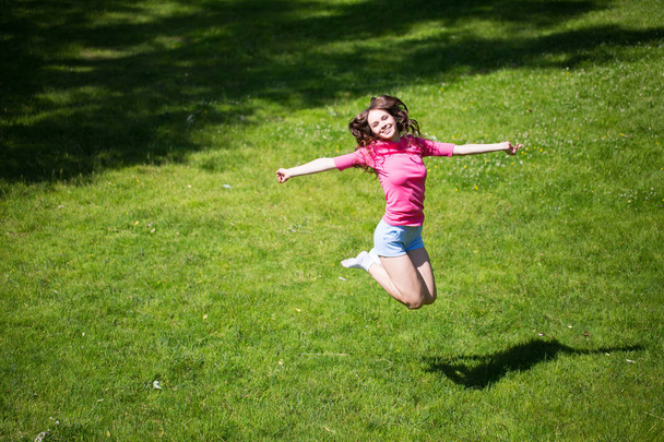 Jeune belle femme sautant dans le parc. Exercice extérieur
. - Photo, image