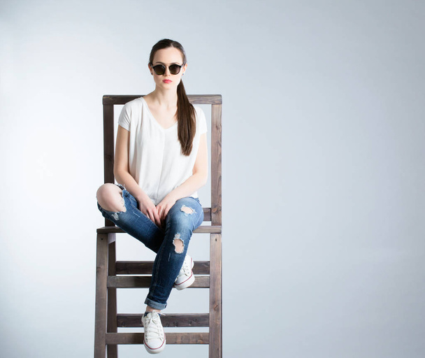 Portrait of attractive young woman sitting. White shirt and jeans. - Foto, afbeelding