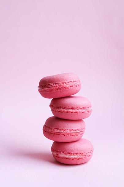 Four pink macaroons on a light pink background, minimal food concept - Foto, Imagen