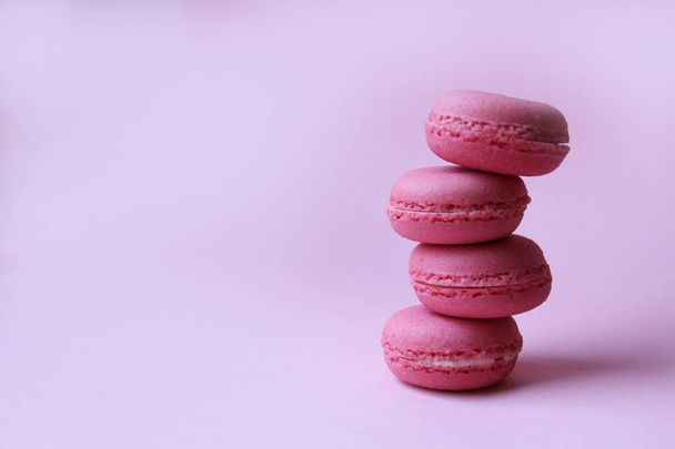 Four pink macaroons on a light pink background, minimal food concept - Фото, зображення
