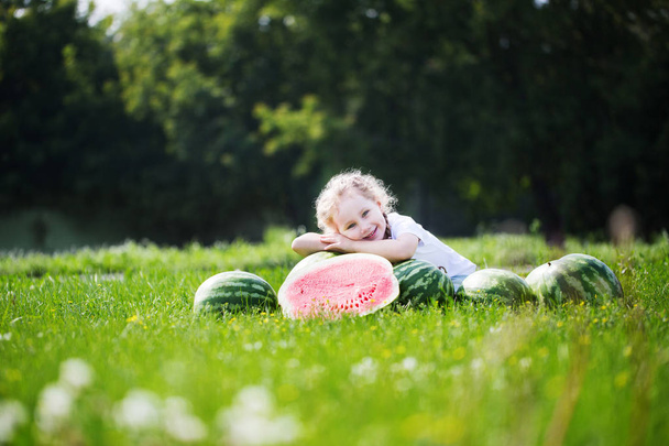 Malá roztomilá holka leží na meloun venku. Zdravé a výživné. - Fotografie, Obrázek