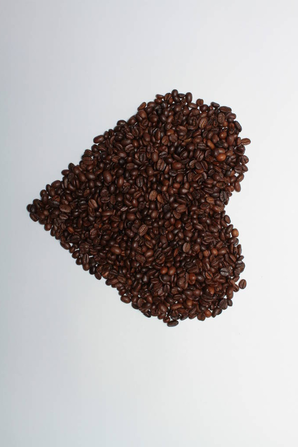 Roasted coffee beans in heart shape on white background - Foto, Imagem