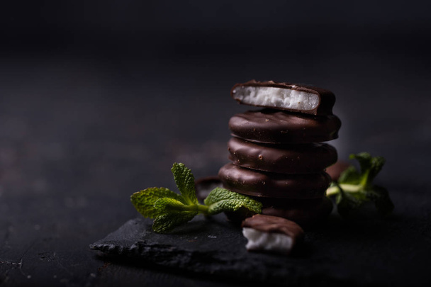 chocolate cookies with mint filling and mint leaves on black background - Фото, изображение