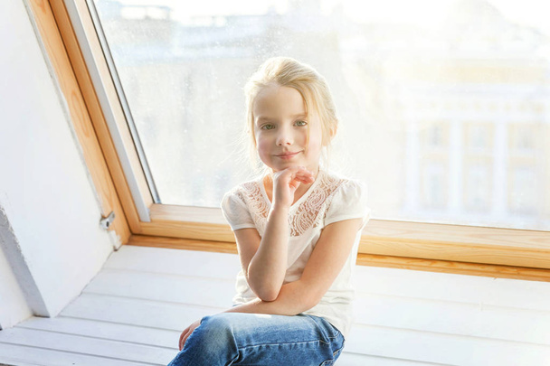 Petite fille assise sur le rebord de la fenêtre
 - Photo, image