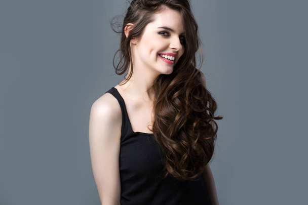 Smiling Woman with long hair on a gray background. Beautiful emotional portrait. - Foto, Imagen