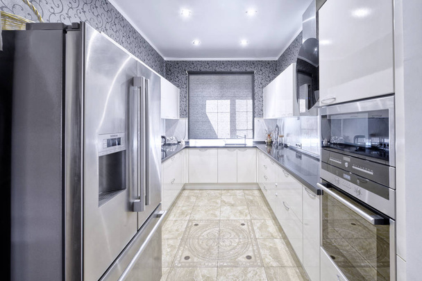 Сучасний дизайн інтер'єру з білою глянсовою кухнею в розкішній квартирі в сірих і білих тонах
. - Фото, зображення