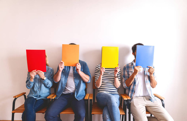 група молодих людей, що покривають обличчя барвистими папками
  - Фото, зображення