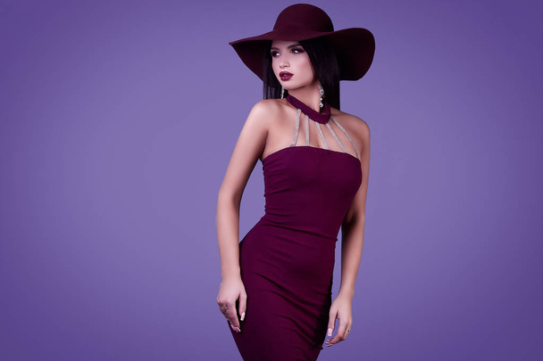 Portrait of elegant beautiful brunette woman in a colorful dress and wide hat isolated on vivid background in studio - Photo, Image