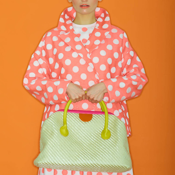 The girl holding a handbag. Isolated on orange background. Shopping addiction - Foto, Imagem
