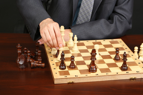 Young business man playing chess on black background - Φωτογραφία, εικόνα