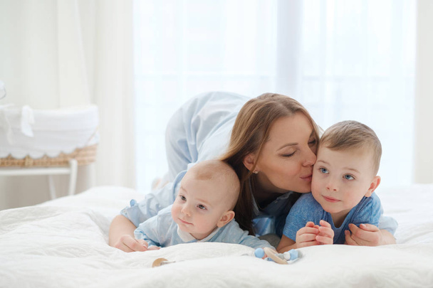 Mãe de meia-idade feliz com seus filhos em uma cama
 - Foto, Imagem