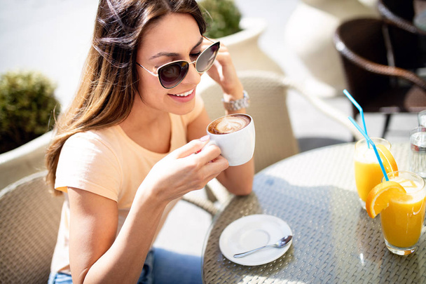 Portrait of happy beautiful woman holding coffee in cafe outdoor - Fotó, kép