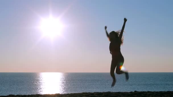 Całego ciała portret szczęśliwy jednej dziewczyny podekscytowany skoki na plaży o wschodzie słońca - Materiał filmowy, wideo