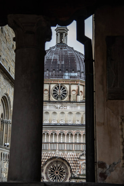 Экстерьер часовни Коллеони. Передний фасад имеет ряд полихромных украшений в кремовых и розовых тонах. Пьяцца дель Дуомо в Бергамо, Италия
. - Фото, изображение