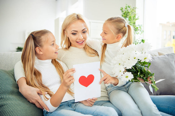 Portrait of nice cute lovely lovable winsome sweet pretty charming attractive mom pre-teen girls sitting on divan reading congrats post card greetings in light white room - Zdjęcie, obraz