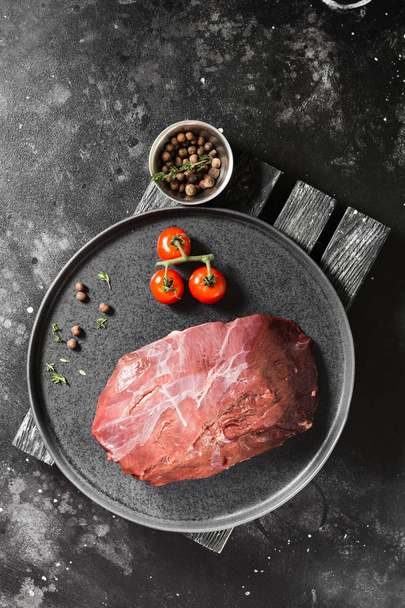 Raw reindeer meat on a black plate on a dark background - Foto, immagini