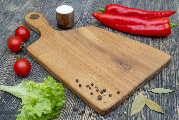 Oak cutting board with vegetables and spices on the kitchen table. - Foto, imagen