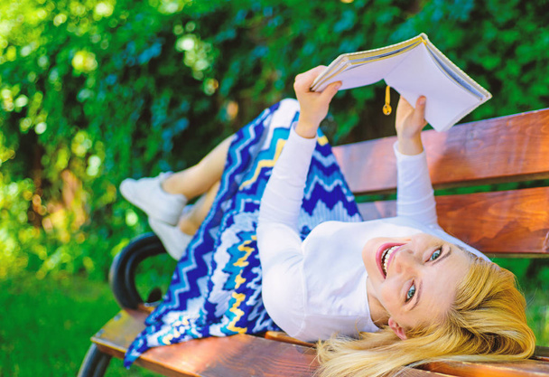 Леди счастливое лицо любит читать. Время самосовершенствоваться. Девушка лежала скамейка парк отдыха с книгой, зеленый фон природы. Женщина проводит досуг с книгой. Девушка читает на открытом воздухе во время отдыха на скамейке
 - Фото, изображение