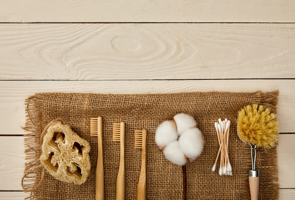 flat lay of  hygiene and care items arranged on sackcloth on white wooden surface, zero waste concept - 写真・画像