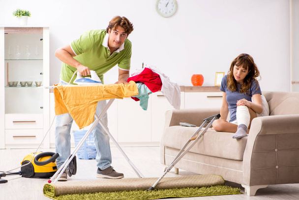 Marido ajudando perna ferida esposa em tarefas domésticas
 - Foto, Imagem