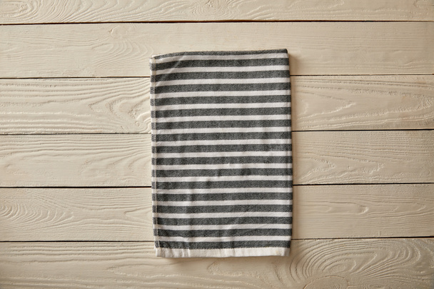 κάτοψη του ριγέ γκρι και λευκή πετσέτα λευκή ξύλινη επιφάνεια - Φωτογραφία, εικόνα