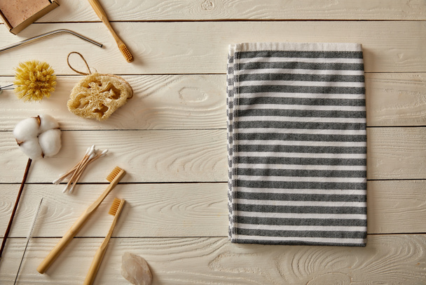 top view of different hygiene and care items and striped towel on white wooden surface, zero waste concept - 写真・画像