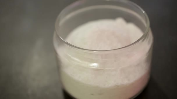 female hand covers the transparent jar of salt, which stands on a black table - Materiaali, video