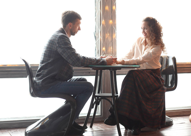 beautiful young couple sitting at a table in a cozy cafe - Foto, Imagem