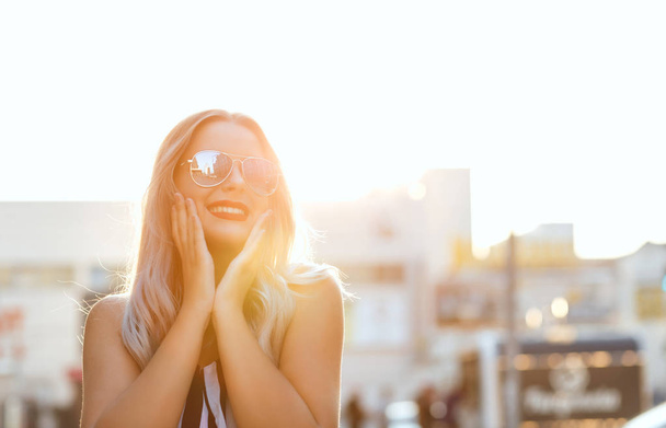 Lifestyle δρόμου πορτρέτο του όμορφη χαρούμενη κοπέλα φορώντας γυαλιά, θέτοντας σε ηλιόλουστο απόγευμα. Κενός χώρος - Φωτογραφία, εικόνα