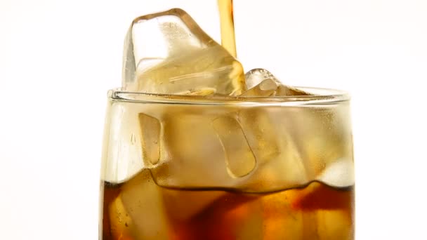 Extreme close up of pouring carbonated cola soft drink in transparent glass with ice cubes until full over white background, low angle side view, slow motion - Footage, Video