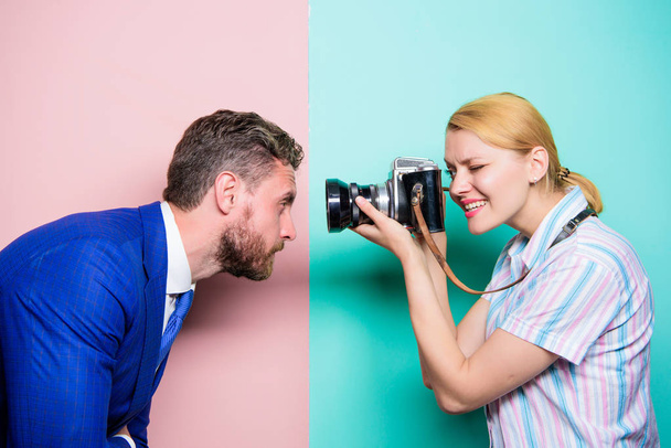 The power behind the picture. Businessman posing in front of female photographer. Pretty woman using professional camera. Photographer shooting male model in studio. Fashion shooting in photo studio - Foto, Imagen