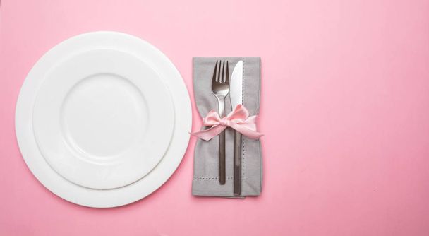 Table place setting in pink. Gray linen napkin with ribbon and white plates on pink color background, top view, copy space - Фото, зображення
