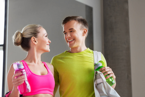 sportive couple with water bottles and bag in gym - Фото, зображення