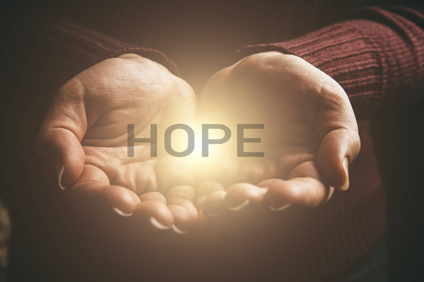 Das Wort Hoffnung in abstraktem Licht in weiblichen Händen bietet Hilfe, Schutz und Unterstützung. Hoffnung teilen - Foto, Bild