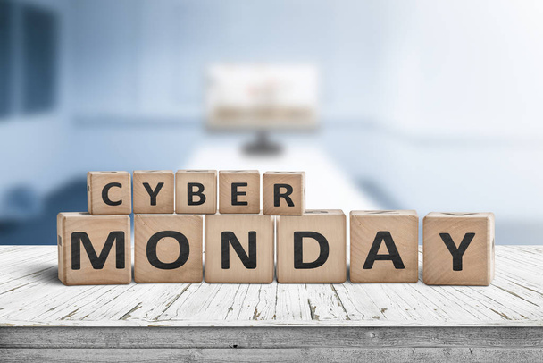Cyber monday sign on a wooden desk with a monitor in a blue room in the background - Fotoğraf, Görsel