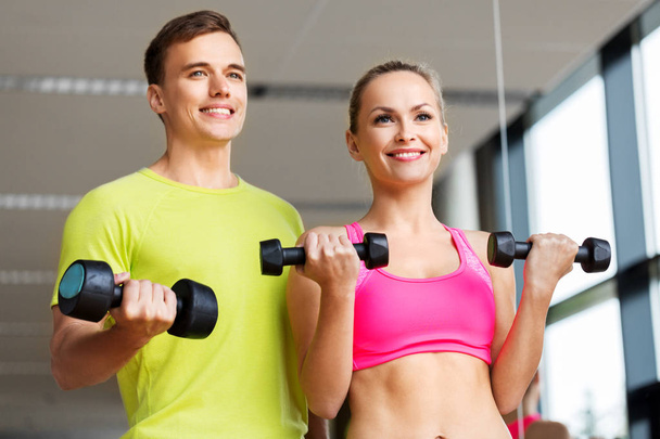 couple with dumbbells exercising in gym - Foto, Imagem