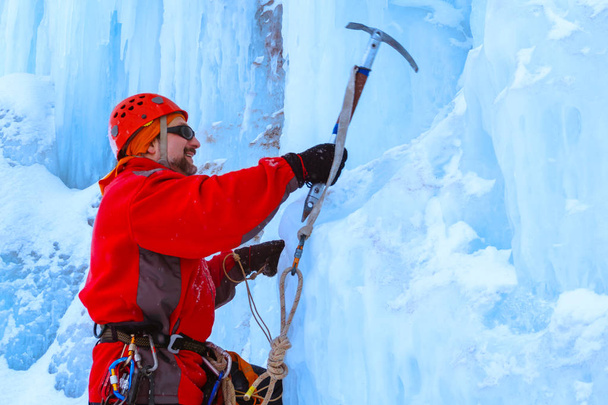 αναρριχητής με πάγο ax είναι κάνει μια ανάβαση ενός τοίχου χιονισμένο πάγου, μισού μήκους πορτραίτο - Φωτογραφία, εικόνα