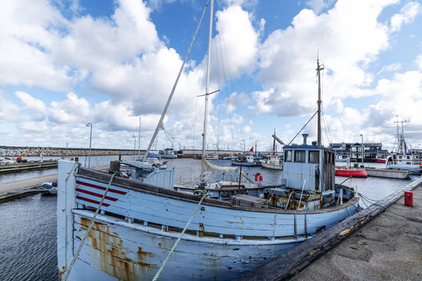Vieux bateau de pêche traditionnel dans un port scandinave sous un ciel bleu nuageux
 - Photo, image