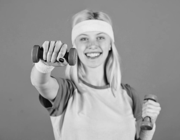 Sport motivation concept. Woman exercising with dumbbells. Exercises with dumbbells. Workout with dumbbells. Biceps exercises for women step by step guide. Girl strong hold dumbbells wear wristbands - Фото, изображение