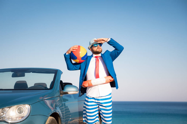 Successful young businessman on a beach. Man standing in the cabriolet classic car. Summer vacations and freedom travel concept - Photo, Image