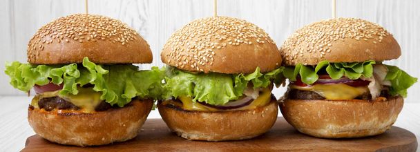 Domácí cheeseburger na rustikální dřevěné desce pomocí bílých dřevěných povrchů, boční pohled. Closeup. - Fotografie, Obrázek