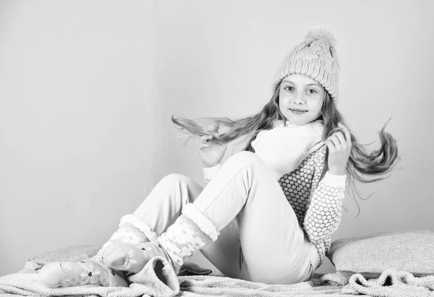 Kid smiling fashion model. Kid girl wear cute knitted fashionable hat and comfortable cozy clothes. Winter fashion concept. Girl long hair relaxing pink background. Winter fashion for children - Φωτογραφία, εικόνα
