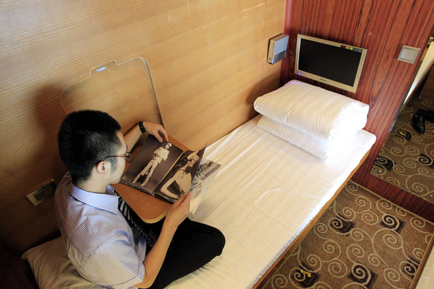A Chinese man reads a magazine on the bed in a sleepbox at the XiAn Xianyang International Airport in XiAn city, northwest Chinas Shaanxi province, 10 July 2012 - Foto, Imagem