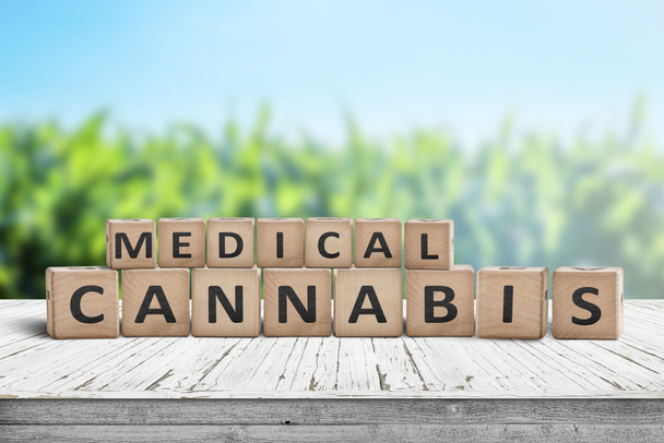 Signe médical de cannabis sur un bureau naturel avec un champ d'herbes en arrière-plan
 - Photo, image