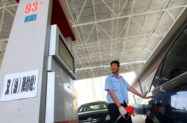 A Chinese staff member refuels a car at a gas station in Jimo city, east Chinas Shandong province, 7 June 2012 - Foto, imagen