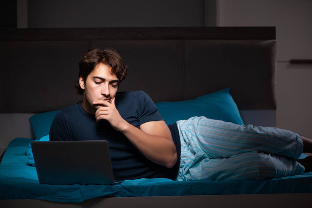 Homme travaillant sur ordinateur portable la nuit au lit
 - Photo, image