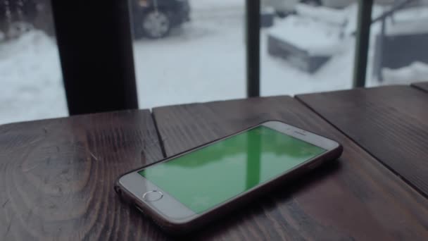 Ο άνθρωπος τα χέρια πληκτρολογώντας στο κινητό πράσινη οθόνη στο ξύλινο τραπέζι στην καφετέρια. - Πλάνα, βίντεο