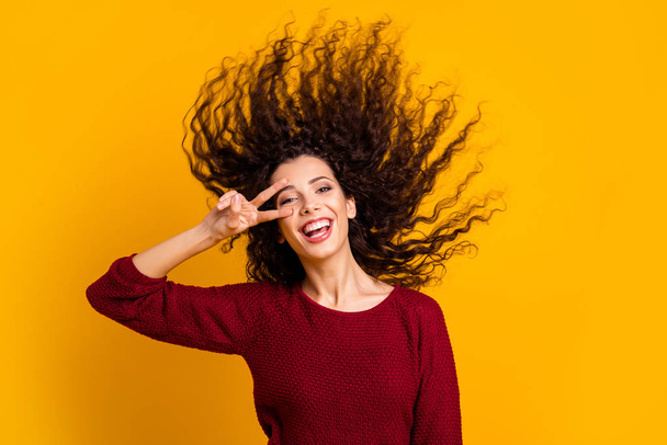 Close up photo amazing charming her she lady hair flight show v-sign near eye careless cheerful funky playful wearing red knitted sweater clothes outfit isolated yellow bright background - Фото, зображення