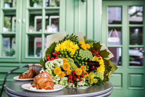 Bouquet di fiori colorati e dessert in tavola. 8 marzo giornata della donna. Alstromeriya, loto, iperico, eustoma, celosia. Primo piano foto
 - Foto, immagini