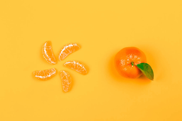 slices of mandarin or tangerine with leaves isolated on orange background. Flat lay, top view. Fruit composition - Foto, afbeelding